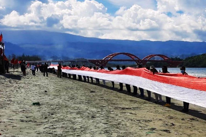 podiumnews.com-Pemuda Papua Bentangkan Bendera Merah Putih Sepanjang Satu Kilo Meter